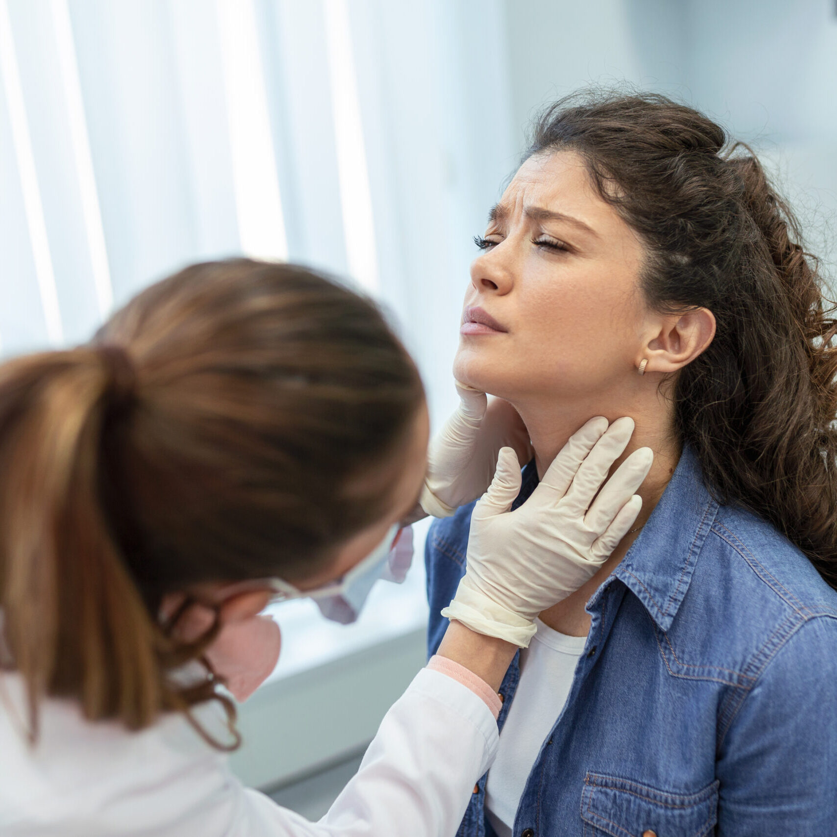 Concept of professional consultation in therapist system. Close up portrait of doctor woman examining tonsils of young lady in medical office